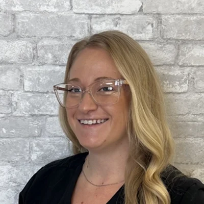 Jessica smiling in front of a brick wall.
